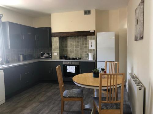 a kitchen with a table and chairs and a kitchen with black cabinets at Comfortable home, town centre, free parking,Multiple Rooms in Cheltenham