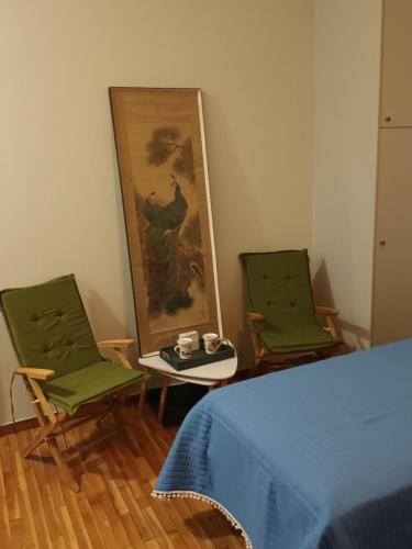 a bedroom with two chairs and a table and a painting at Στούντιο Διπλα στην Ακρόπολη in Athens