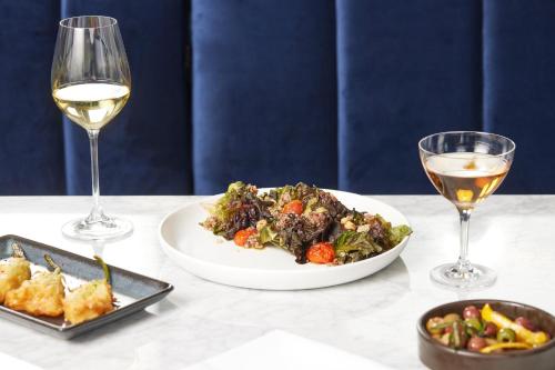 a table with a plate of food and two glasses of wine at Kimpton - The Forum Hotel by IHG in Charlottesville