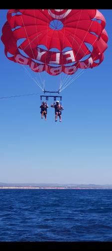 two people on a red parachute over the ocean at AlbufeiraSun, arrive as a guest leave as a friend. in Albufeira