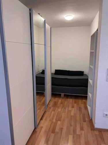 Cette chambre dispose d'un lit noir et de parquet. dans l'établissement Schönes Studio in Offenbach mit Balkon, à Offenbach-sur-le-Main