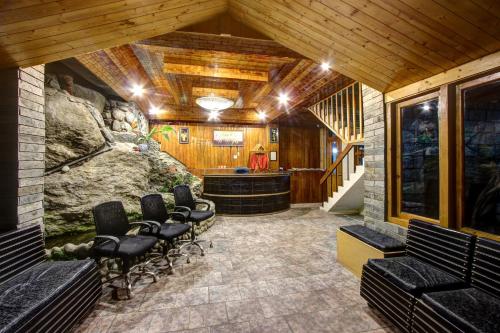 a room with chairs and a bar in a building at Hotel Shishamaati in Kulu