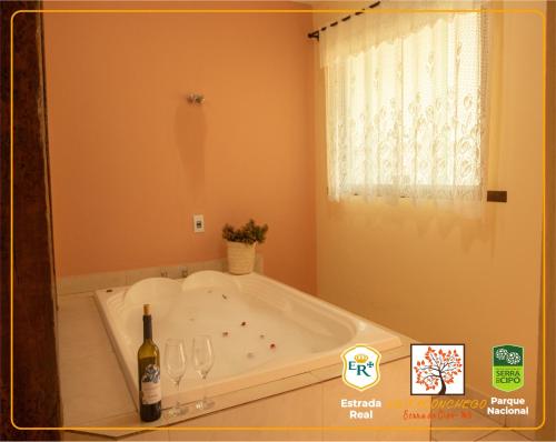 a bath tub with a bottle of wine and glasses at POUSADA VILA ACONCHEGO- Sossego- Em Meio Há Mata Nativa- by MARCOS MICOZZI in Serra do Cipo