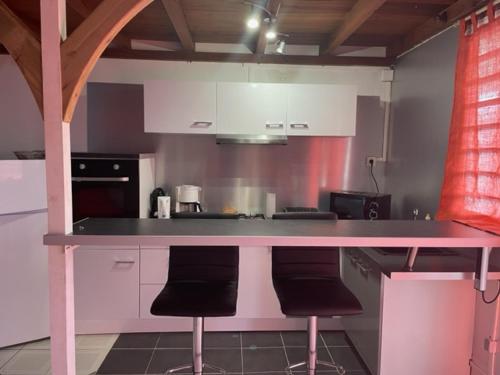 una cocina con encimera rosa y 2 taburetes en Residence Chez Marraine Maison BERTILI en Le Gosier