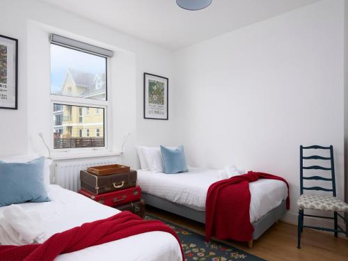 sypialnia z 2 łóżkami, krzesłem i oknem w obiekcie Saltwater Cottage w mieście Torquay