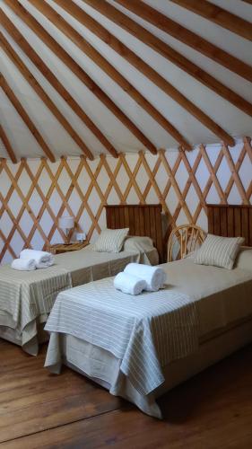 two beds in a room with a triangular ceiling at Yurtas Ivirareta Glamping in Garupá