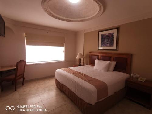 a bedroom with a bed and a window and a desk at Savoy Express in Torreón