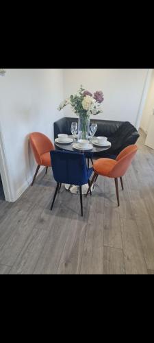 a table with chairs and a vase of flowers on it at Modern 2 Bedroom Flat With Garden LONDON in Northolt