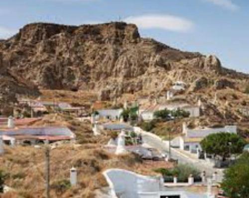 Une petite ville avec une montagne en arrière-plan dans l'établissement la cueva de guadix, à Guadix