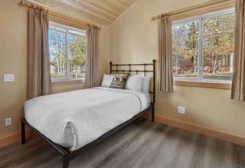 ein Schlafzimmer mit einem Bett und zwei Fenstern in der Unterkunft Patricia Lake Bungalows in Jasper