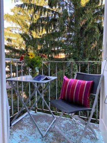 a chair with a pink pillow and a table on a balcony at Altstadthaus Cityappartements in Graz