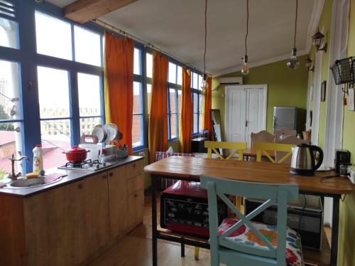 a kitchen with a wooden table and some windows at Hostel ERA in Tbilisi City