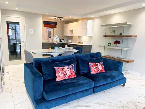 un sofá azul en una sala de estar con cocina en Modern Luxurious Apartment w/ Patio Balcony & View, en Jordanstown