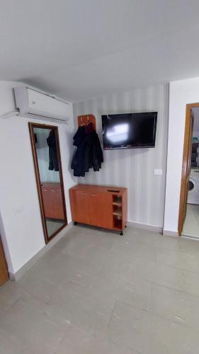 Habitación con TV en la pared y espejo. en Apartament MeliMe, en Roman