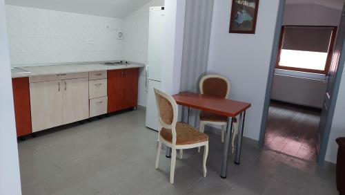 a kitchen with a wooden table and two chairs at Apartament MeliMe in Roman