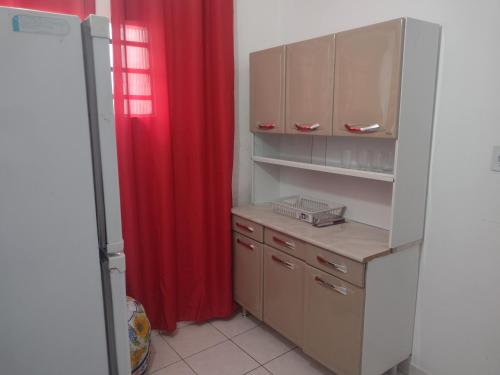 a kitchen with a red curtain and a refrigerator at Apartamento Encantador in Guaratinguetá