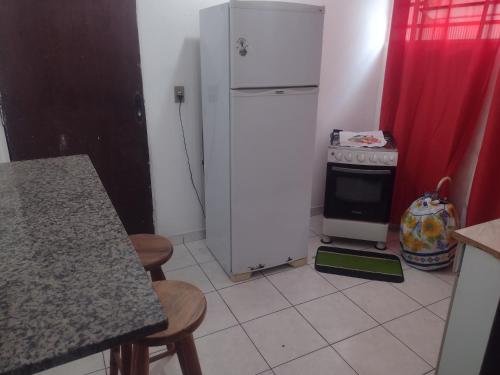 a kitchen with a white refrigerator and a stove at Apartamento Encantador in Guaratinguetá