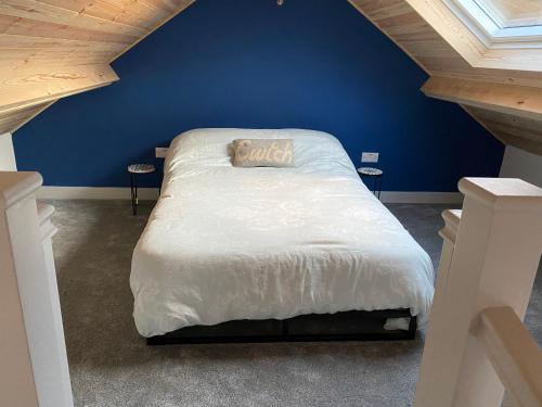 a blue bedroom with a bed with a white comforter at Stonecroft Cwtch in Haverfordwest