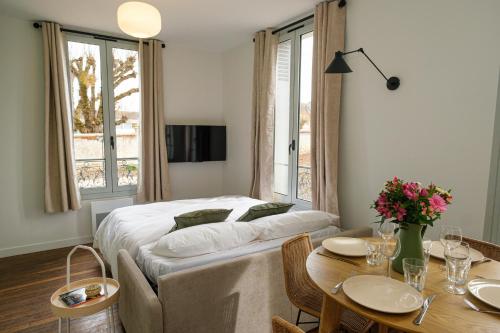a bedroom with a bed and a table and chairs at Villa Forestière Appart Le Ginkgo in Quincy-Voisins