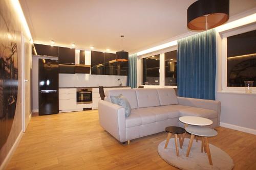 un soggiorno con divano bianco e una cucina di Drzewna Apartamenty -Augustowska a Zielona Góra