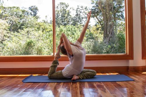 Eine Frau, die eine Yoga-Pose vor einem Fenster macht. in der Unterkunft Hotel Belmar in Monteverde Costa Rica