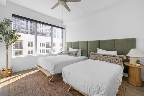 two beds in a room with a large window at Mint House Nashville - The Gulch - Division St in Nashville