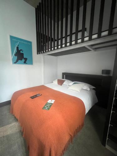 a bedroom with a bed with an orange blanket at Le B Complexe Hôtel in Lozanne
