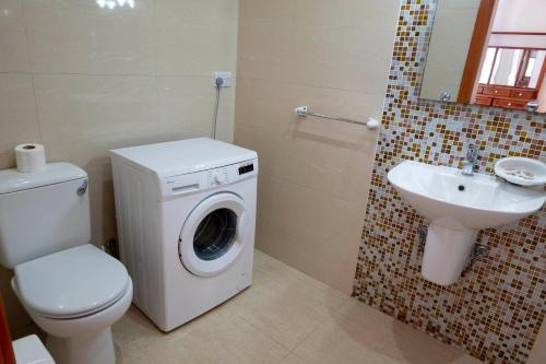 een badkamer met een wasmachine en een wastafel bij Zest Holiday Home in Qala