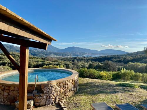 una piscina in un muro di pietra con vista sulle montagne di Bergerie FIORA, Domaine de l Ogliastru a Olmeto