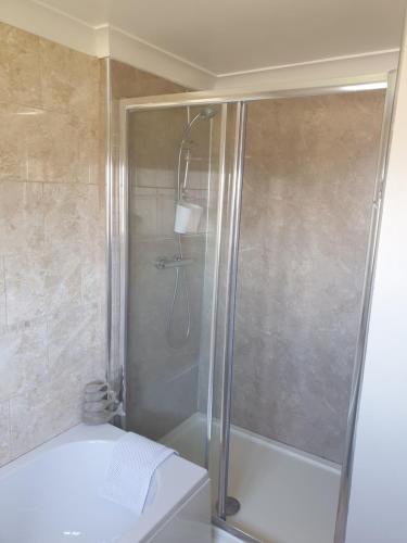 a shower with a glass door in a bathroom at Bader House in Aberporth