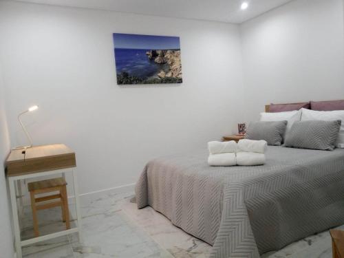 a white bedroom with a bed and a table at Flat in Olhão city center in Olhão