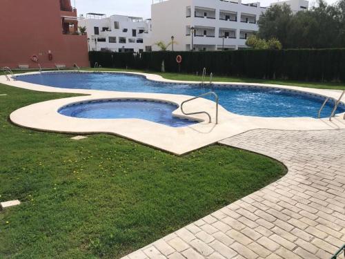 a swimming pool with a sculpture in the grass at Atico con piscina privada y vistas al mar in Vera