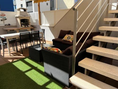 uma varanda com um sofá, uma mesa e escadas em Casa en la playa con piscina em Cubelles