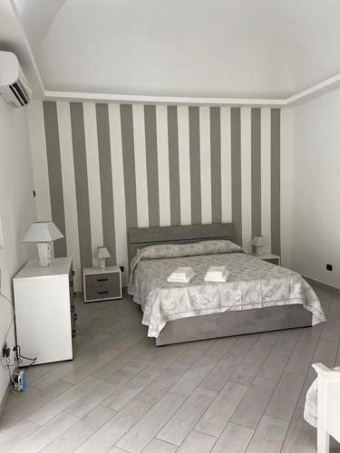 1 dormitorio con cama y pared a rayas en Domus mea, en Boscotrecase