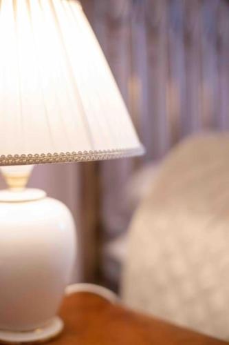 a white lamp sitting on a table next to a bed at Torre delle rondini in Castelnuovo di Farfa