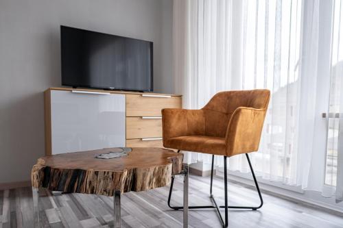 a living room with a table and a chair and a tv at Mike‘s Mosel Lodge in Treis-Karden