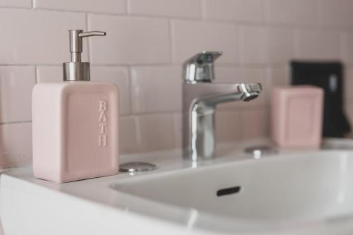 un lavandino in bagno con dispenser di sapone accanto a un rubinetto di Casa Nanni - Pesaro a Pesaro
