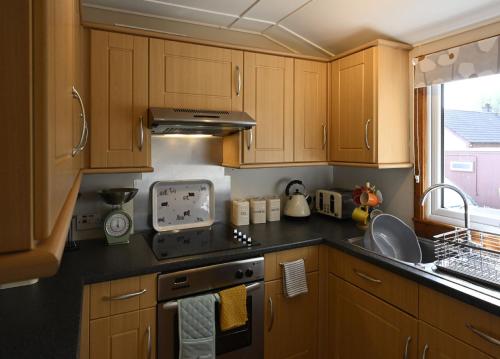 a kitchen with wooden cabinets and a stove top oven at Taigh Nan Daraich in Spean Bridge
