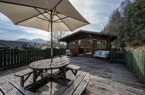 a wooden deck with a picnic table and an umbrella at Taigh Nan Daraich in Spean Bridge