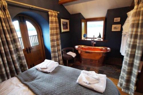 sypialnia z wanną i łóżkiem z ręcznikami w obiekcie Duke of Portland Boathouse on the shore of Lake Ullswater ideal for a romantic break w mieście Pooley Bridge