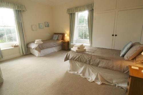 a bedroom with two beds and two windows at Rock Moor House B&B in North Charlton