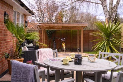 a table and chairs on a patio with a table and cups at The Nest in Brockenhurst