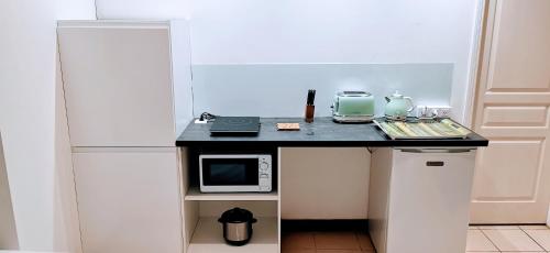 a small kitchen with a black counter with a microwave at EVASION Bungalow Tropical Spa in Sarraméa