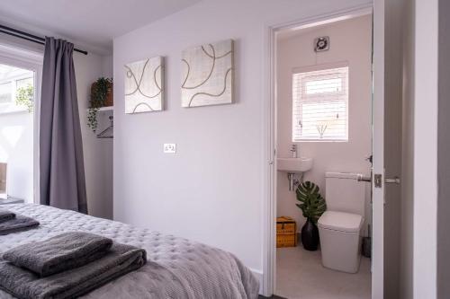 ein weißes Schlafzimmer mit einem Bett und einem Badezimmer in der Unterkunft Captain's Keep in Lymington