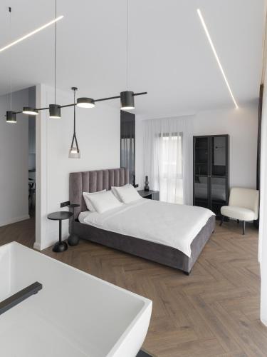 a white bedroom with a bed and a chair at Evo Residence Panoramic in Cluj-Napoca
