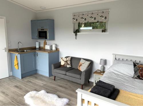 a bedroom with a bed and a kitchen and a couch at Cruachan Cabin in Oban