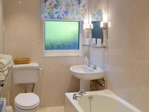 a bathroom with a sink and a toilet and a bath tub at Rowan Cottage-80119 in Catcleugh