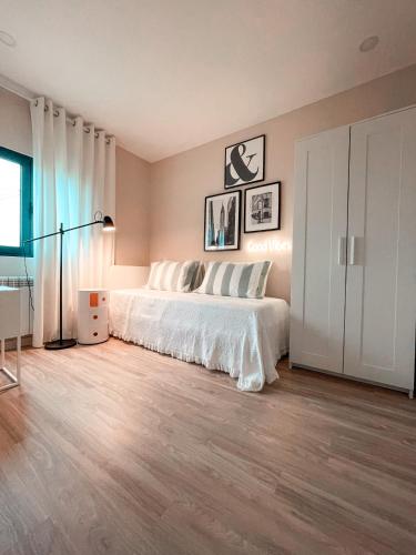 a bedroom with a bed with white sheets and wood floors at Fornas House in Caminha