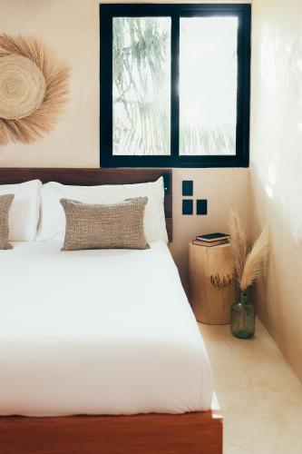 a bedroom with a white bed and a window at Cucu Hotel El Cuyo in El Cuyo