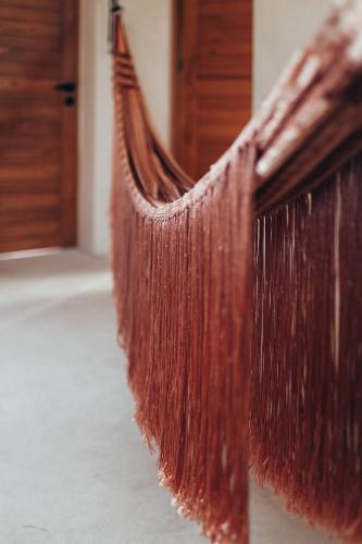a hanging bed with brown hair on the side of a room at Cucu Hotel El Cuyo in El Cuyo